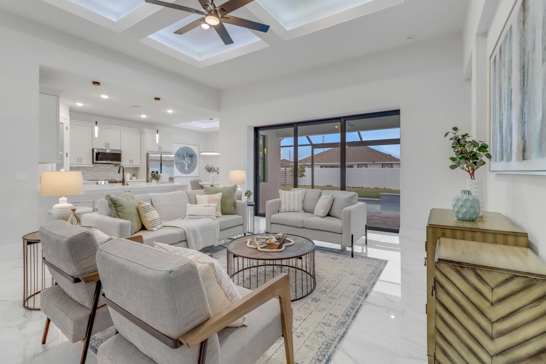 Hardwyn furnished living room with cream sofas, wood-framed chairs, a round coffee table, and illuminated tray ceiling