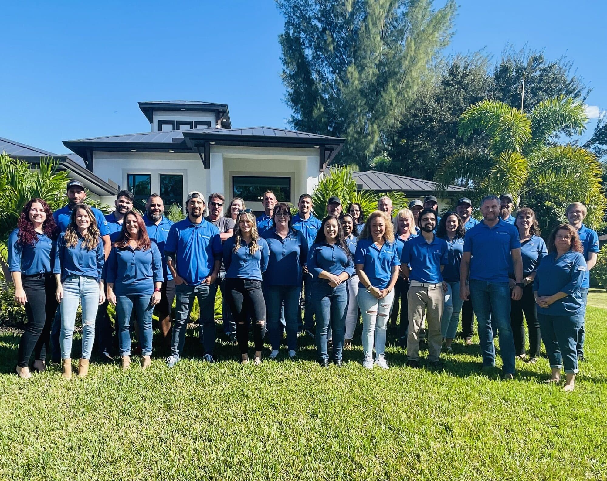 The Sposen team in blue polos standing together in front of a completed home