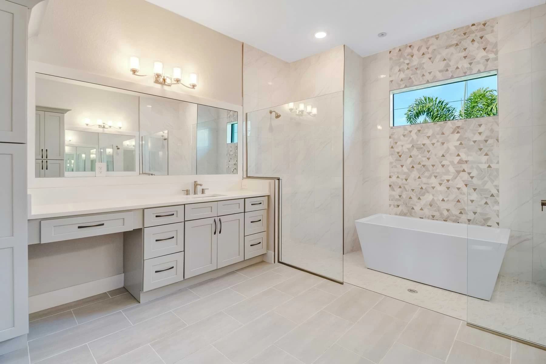 Mira Vista bathroom with a freestanding tub, geometric mosaic accent wall, glass shower, and pale gray vanity