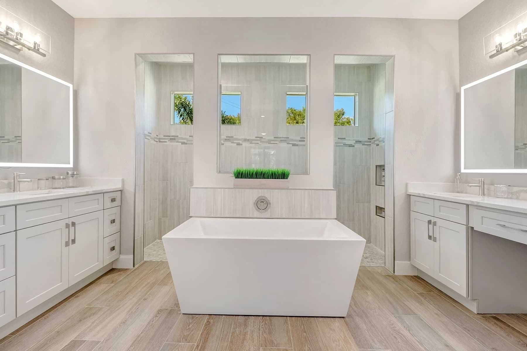 Spica bathroom with a centered freestanding tub, twin vanities, illuminated mirrors, and a walk-through shower