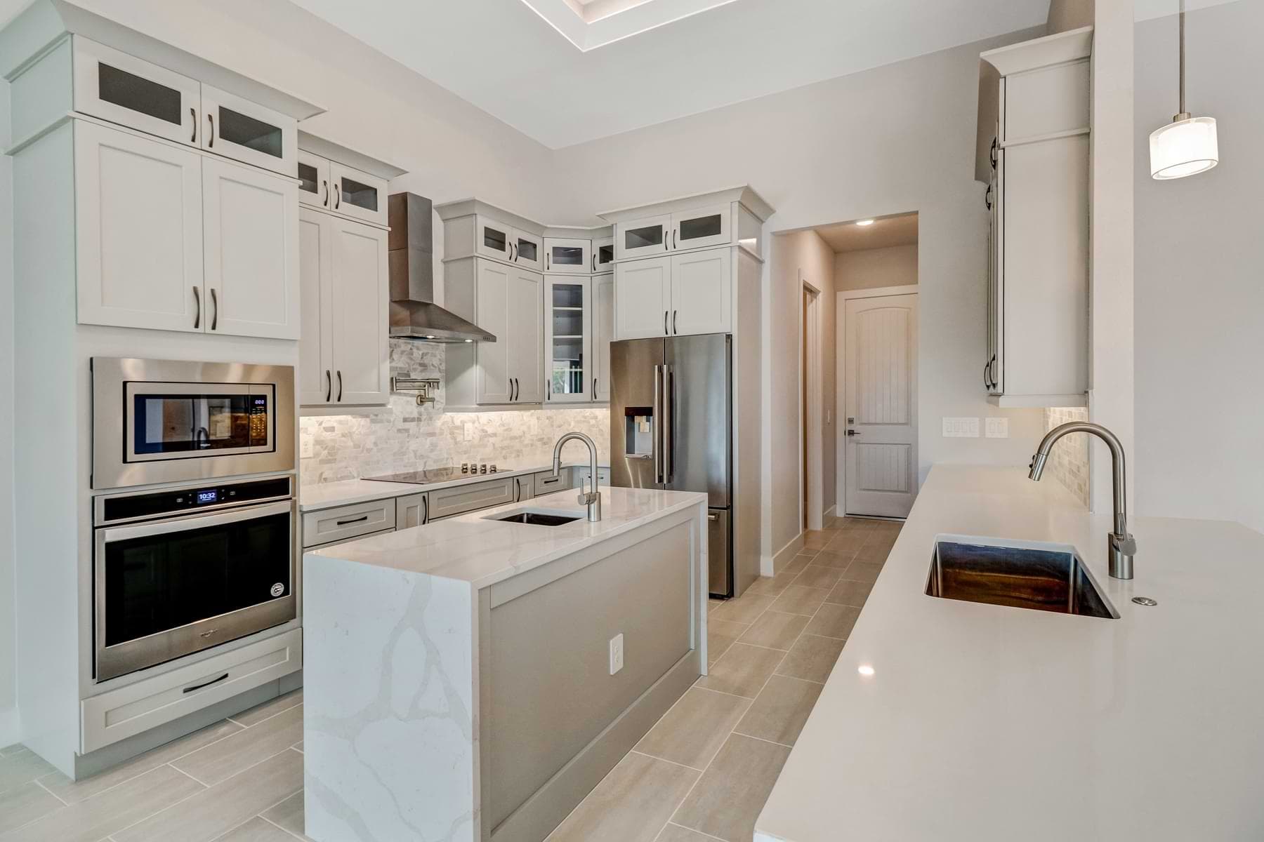 Kitchen with quartz island and stainless appliances in a completed Fort Myers home.