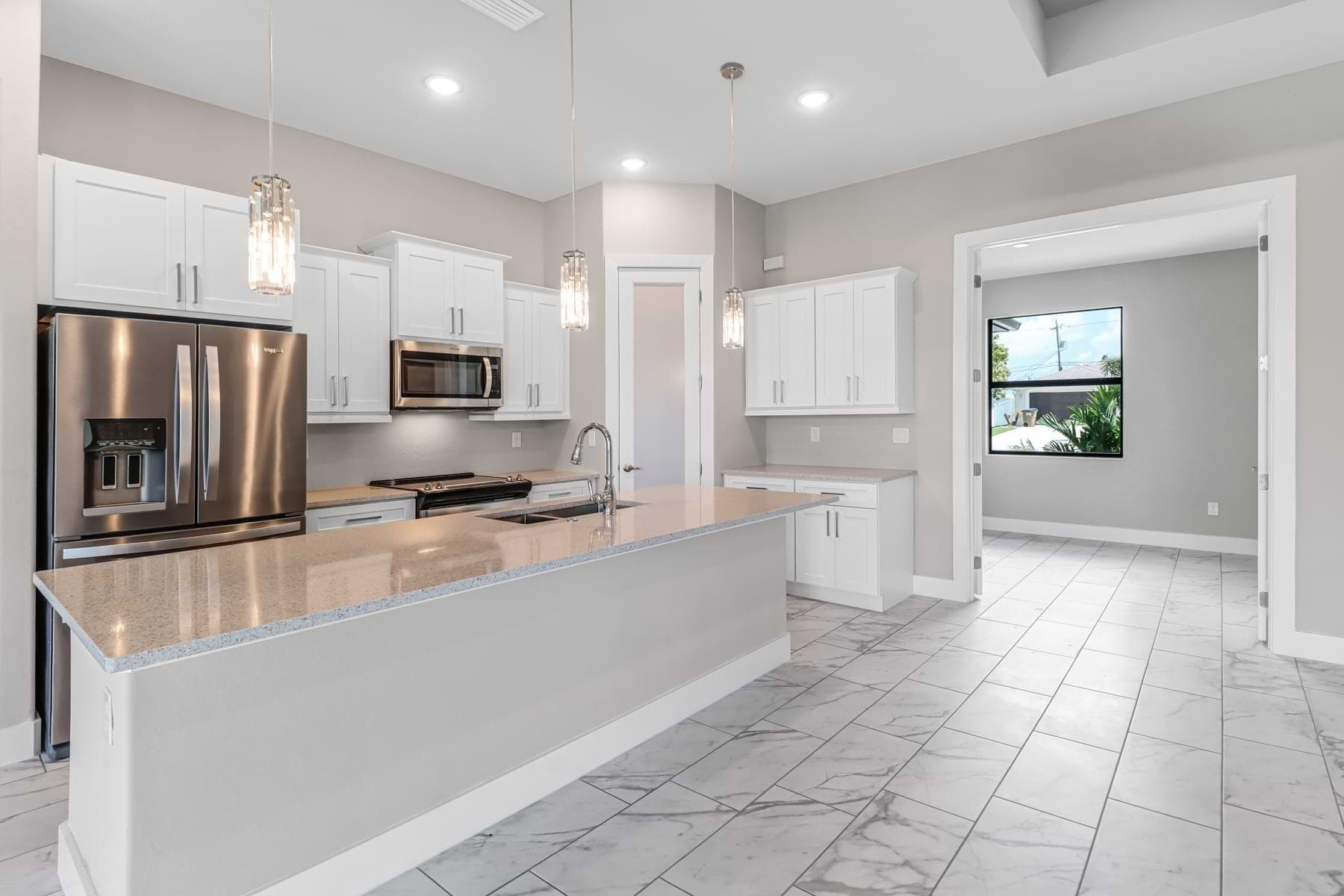 Open kitchen with waterfall island in a completed North Fort Myers home.