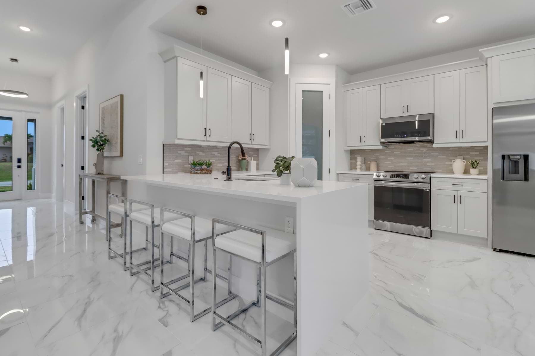 Kitchen with island seating and marble-look tile in a completed Punta Gorda home.