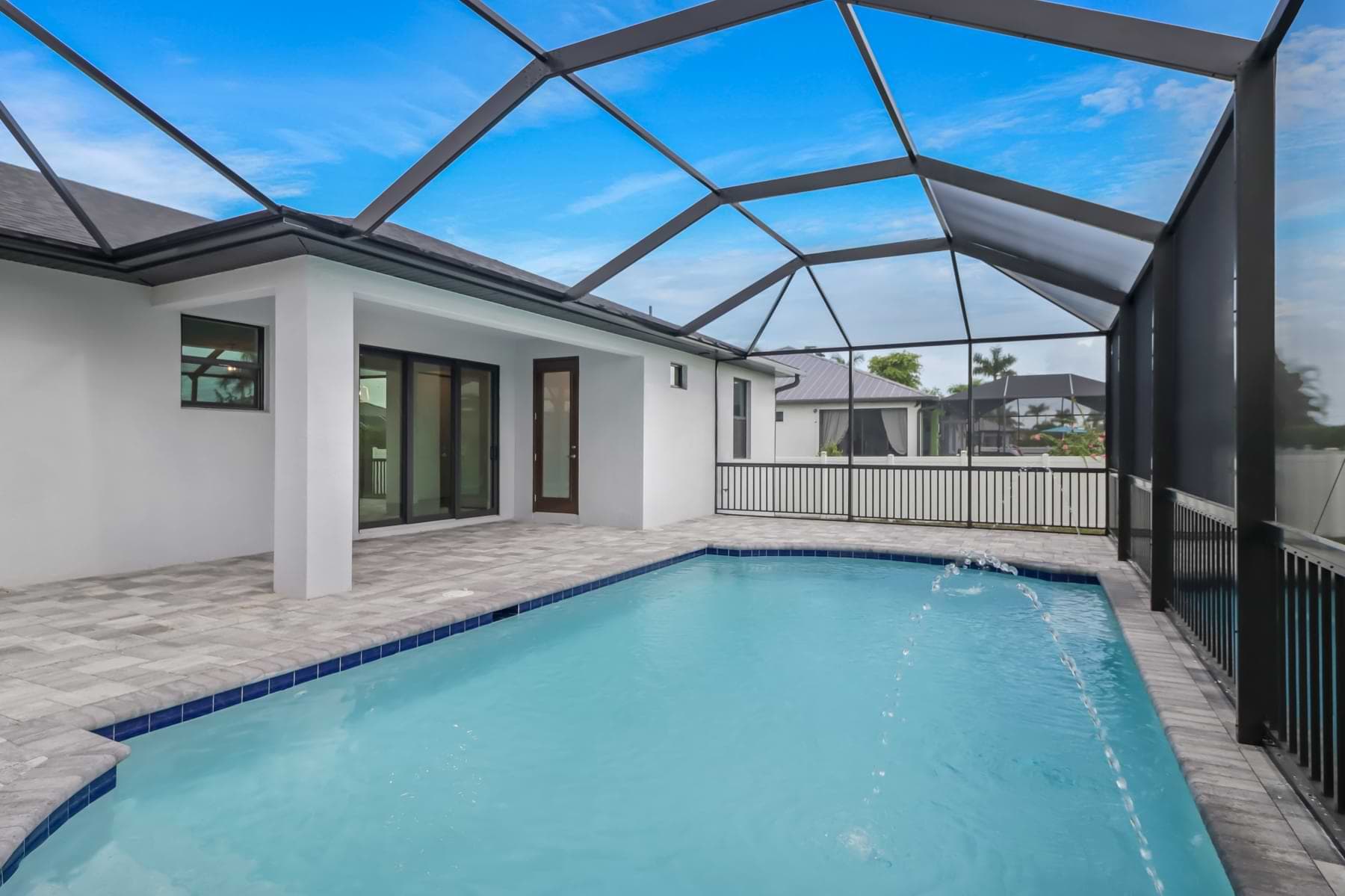 Haven pool with arcing deck jets facing the covered lanai and sliding glass doors
