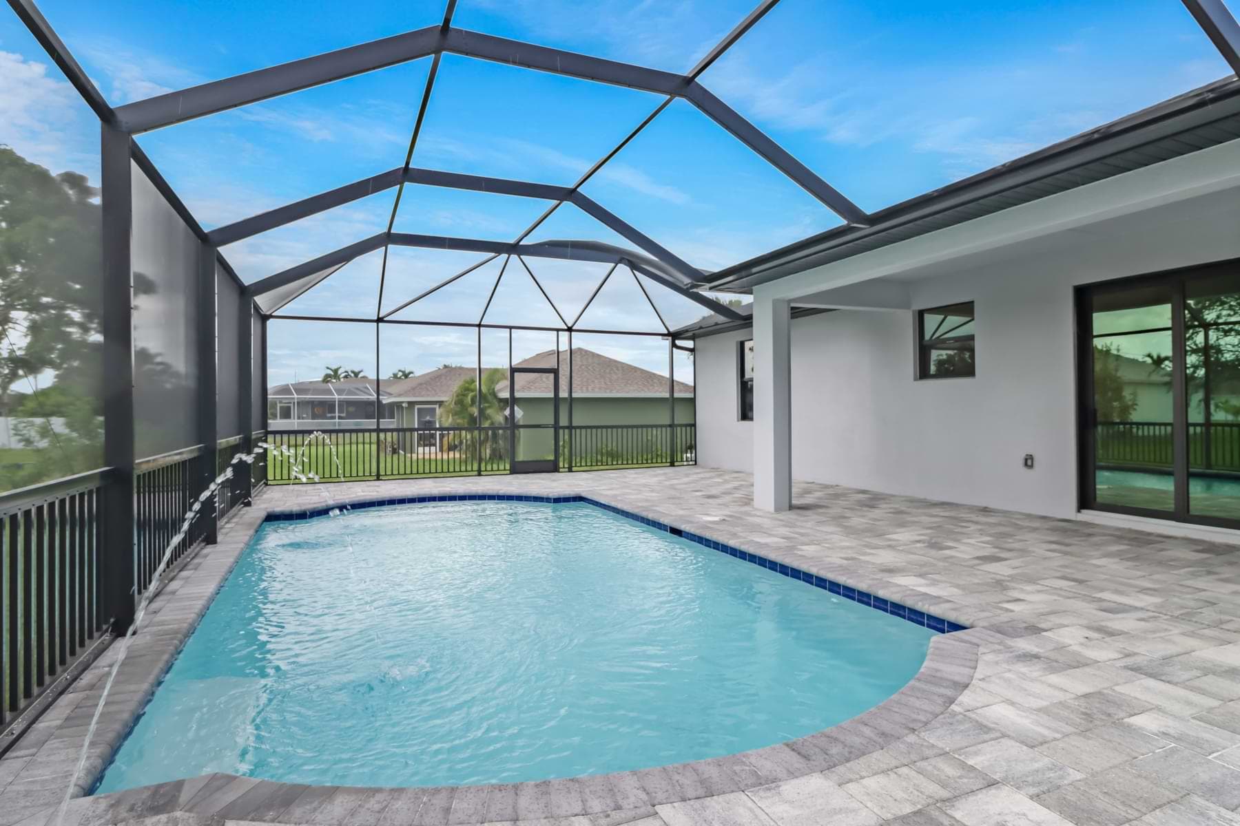 Screened Haven pool with deck jets and gray pavers beside the covered lanai