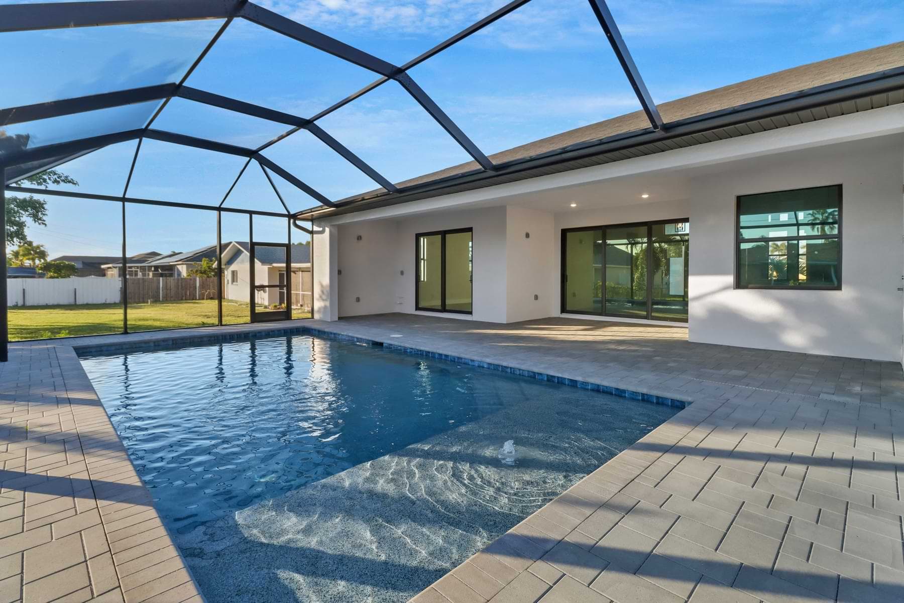 Screened Spica pool with entry steps, a paver deck, and a covered lanai