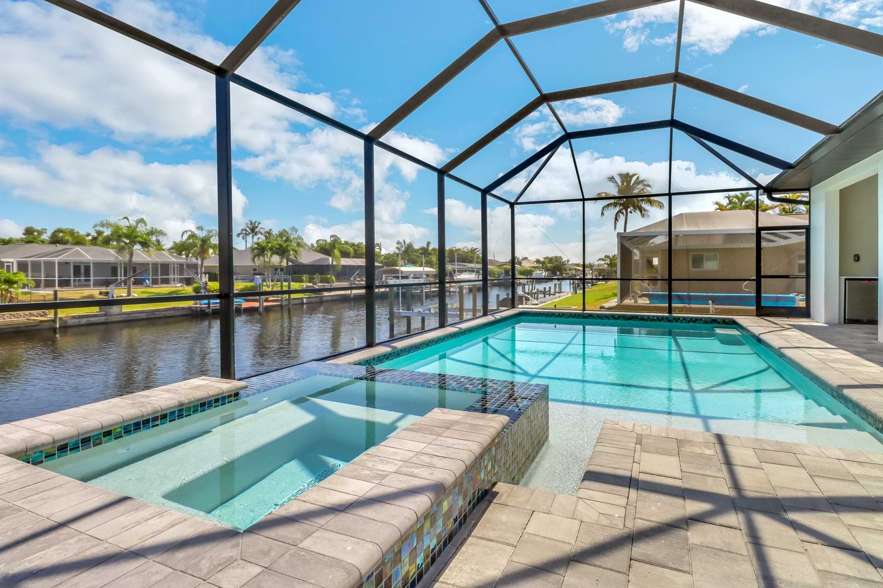 Mira Vista raised spa and screened pool with shallow sun shelf beside a canal
