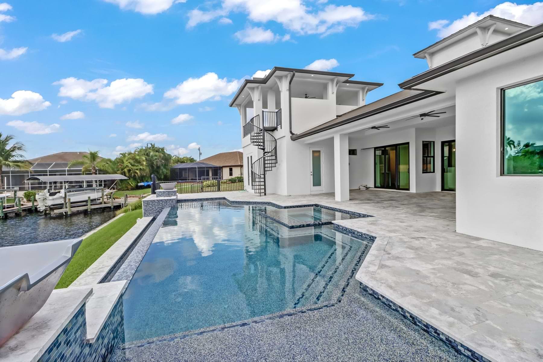 Vista Grande pool and spa beside a covered lanai and spiral staircase overlooking a canal