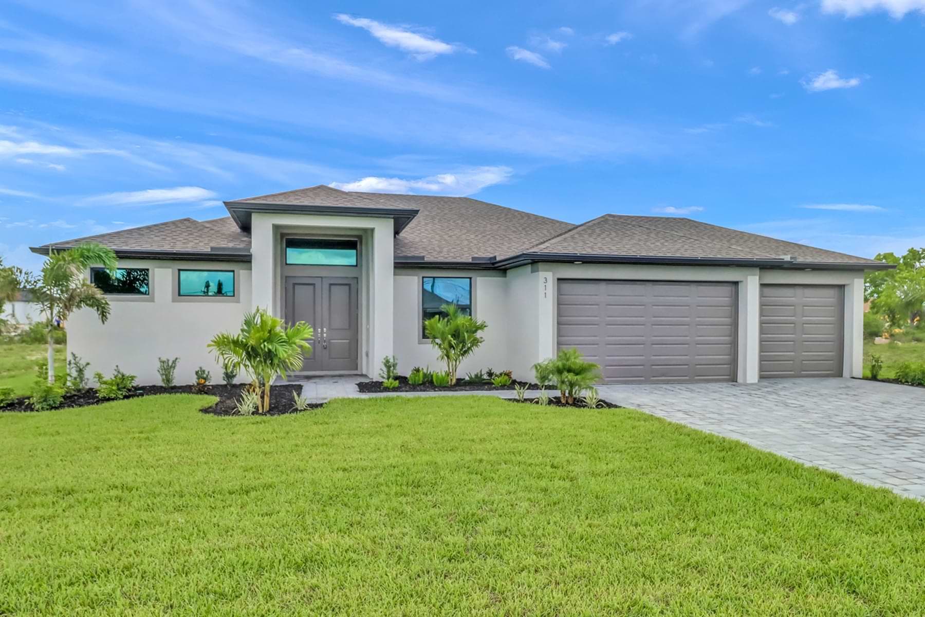 Front exterior of the Sposen Signus model home with landscaped yard and triple garage
