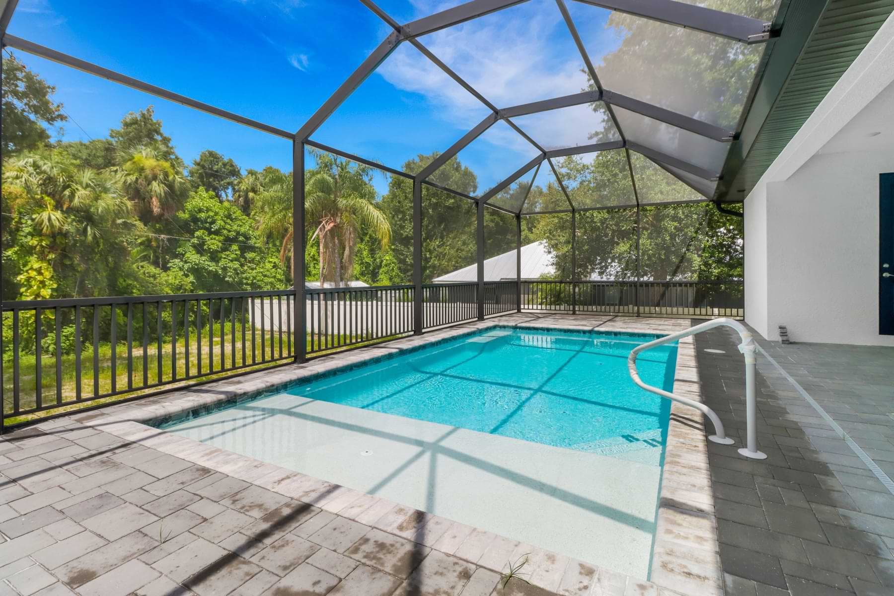 Screened pool surrounded by mature trees in a completed Alva home.